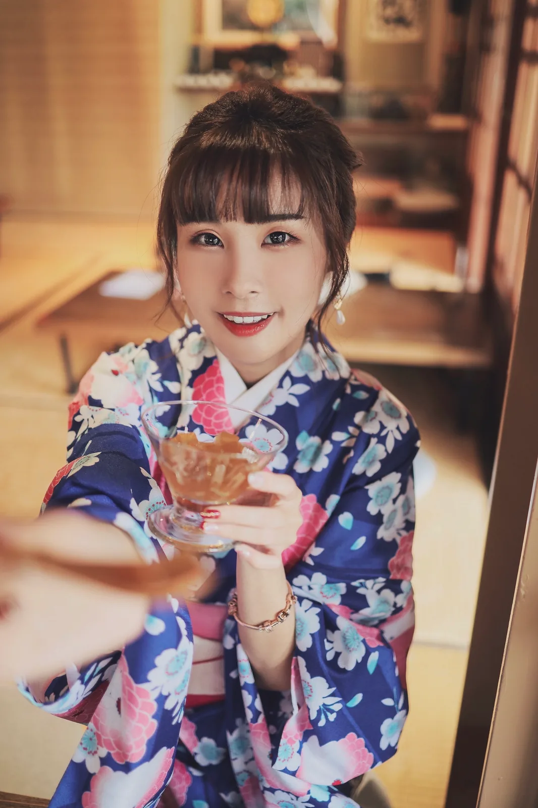 泥泥汝手举玻璃茶杯朝向镜头的俯拍画面